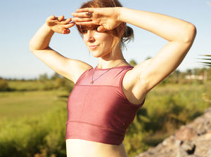 Medium build woman wearing fitted pink fitted crop top with high neck.