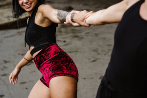 Medium build woman wearing fitted black cotton yoga crop top and velvet shorts.